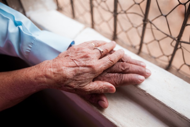 An older person holding the hand of a younger person