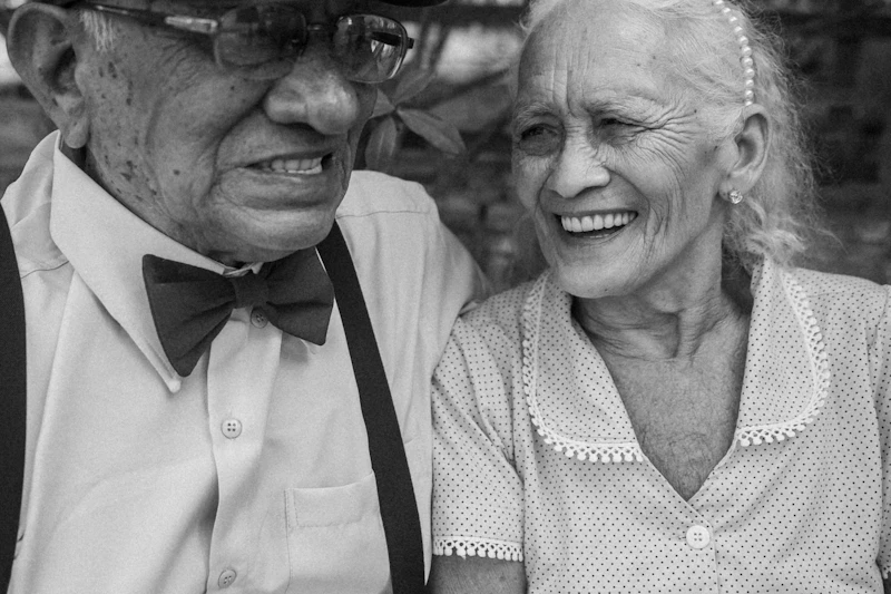 An elderly man and woman smiling together, posing for a photo