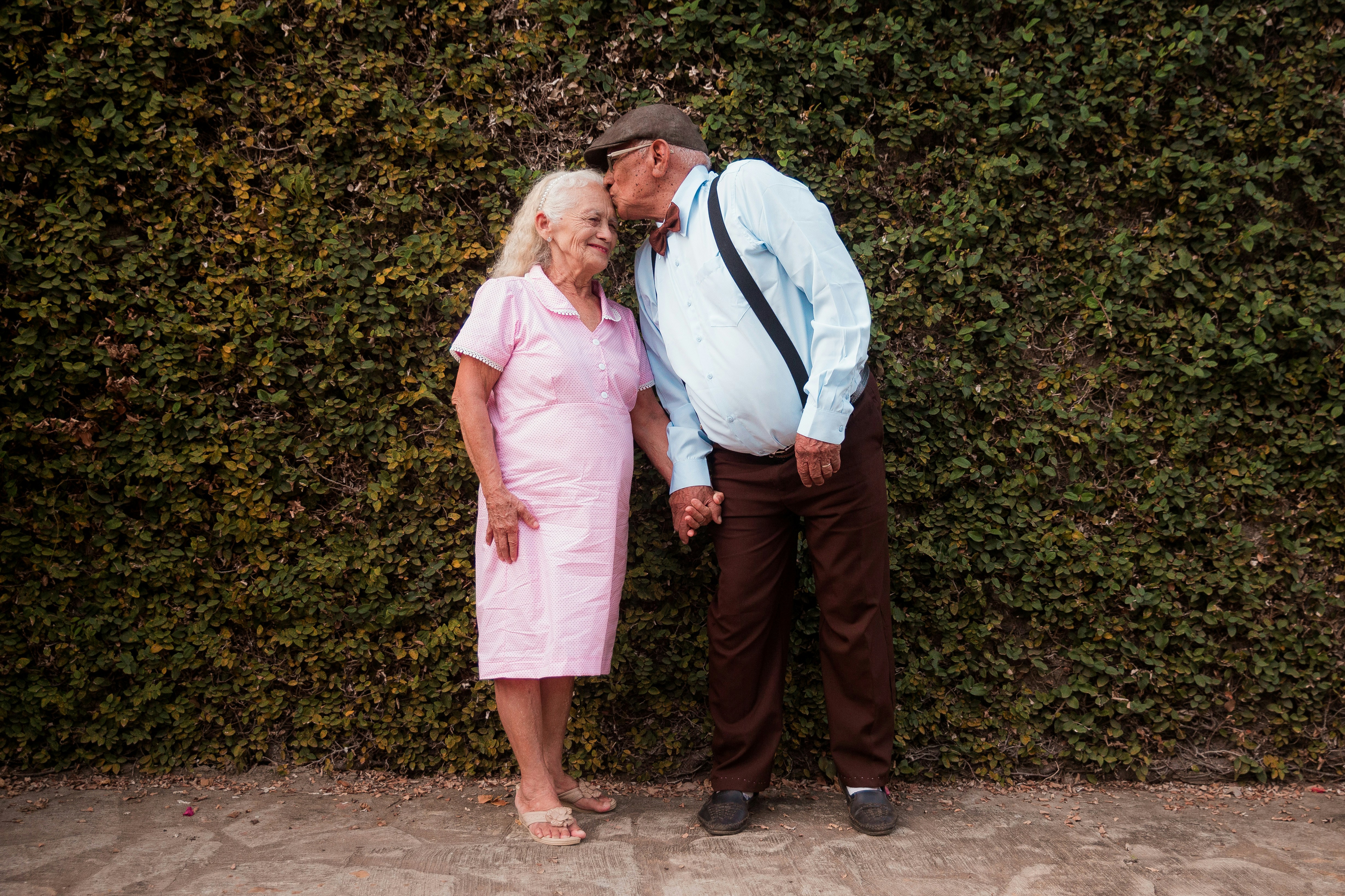 A man and a woman standing in front of a hedge