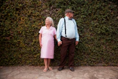 A man and a woman standing in front of a hedge