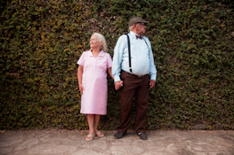 A man and a woman standing in front of a hedge