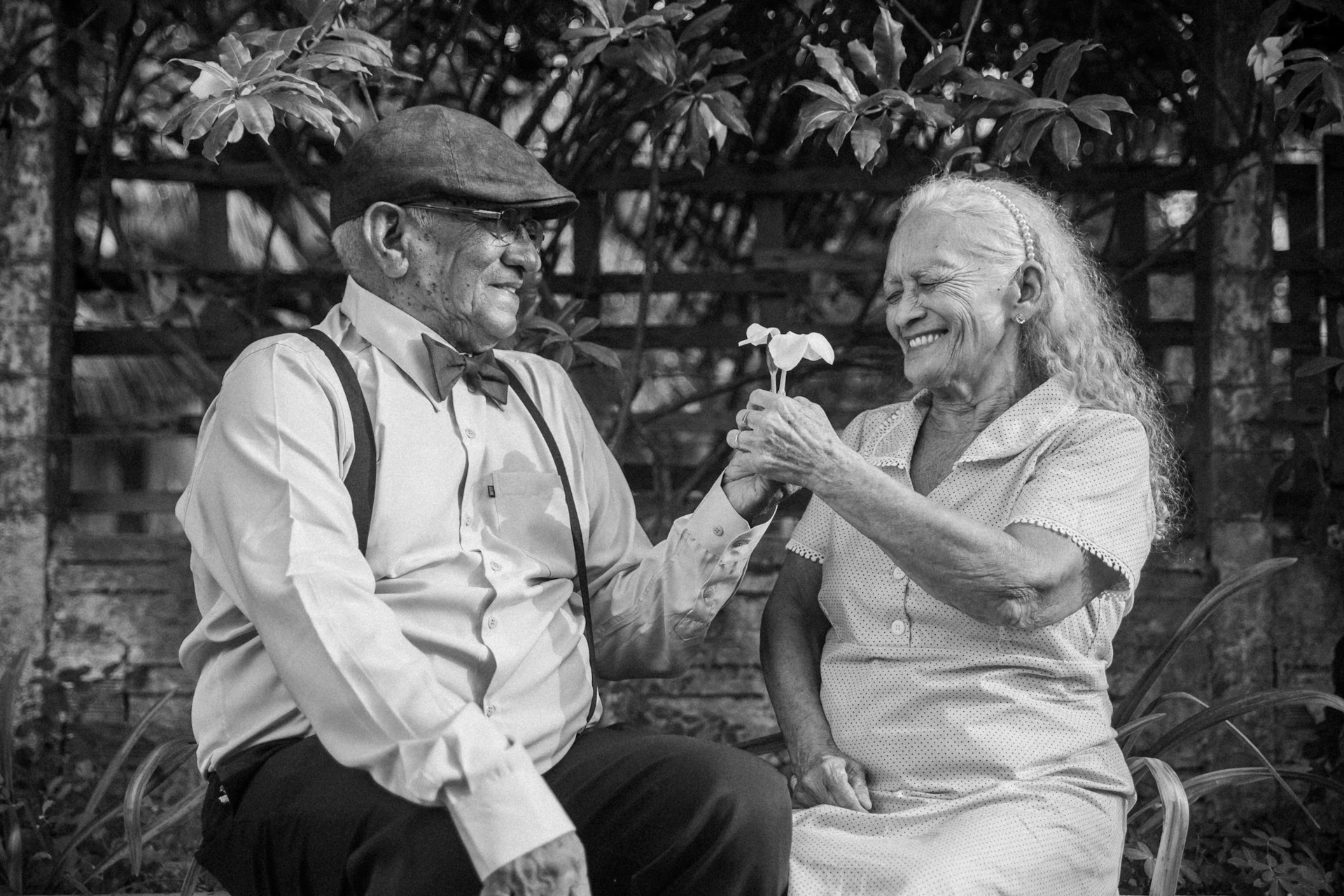 A black and white photo of two people sitting on a bench
