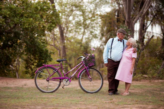A man and a woman standing next to a purple bike