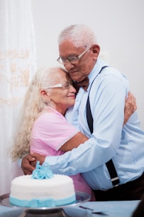 A man and woman hugging each other in front of a cake
