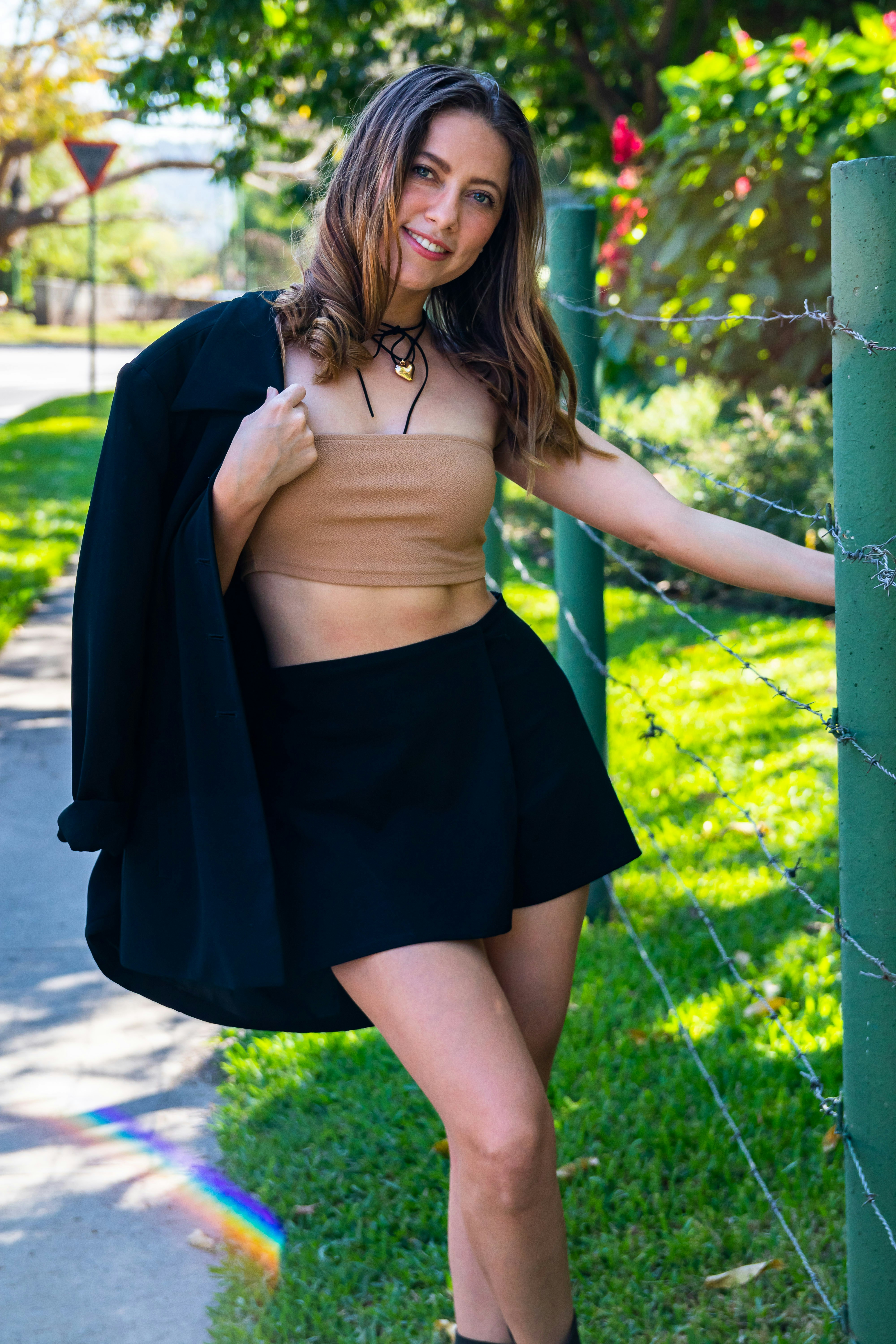 A woman leaning against a fence posing for a picture