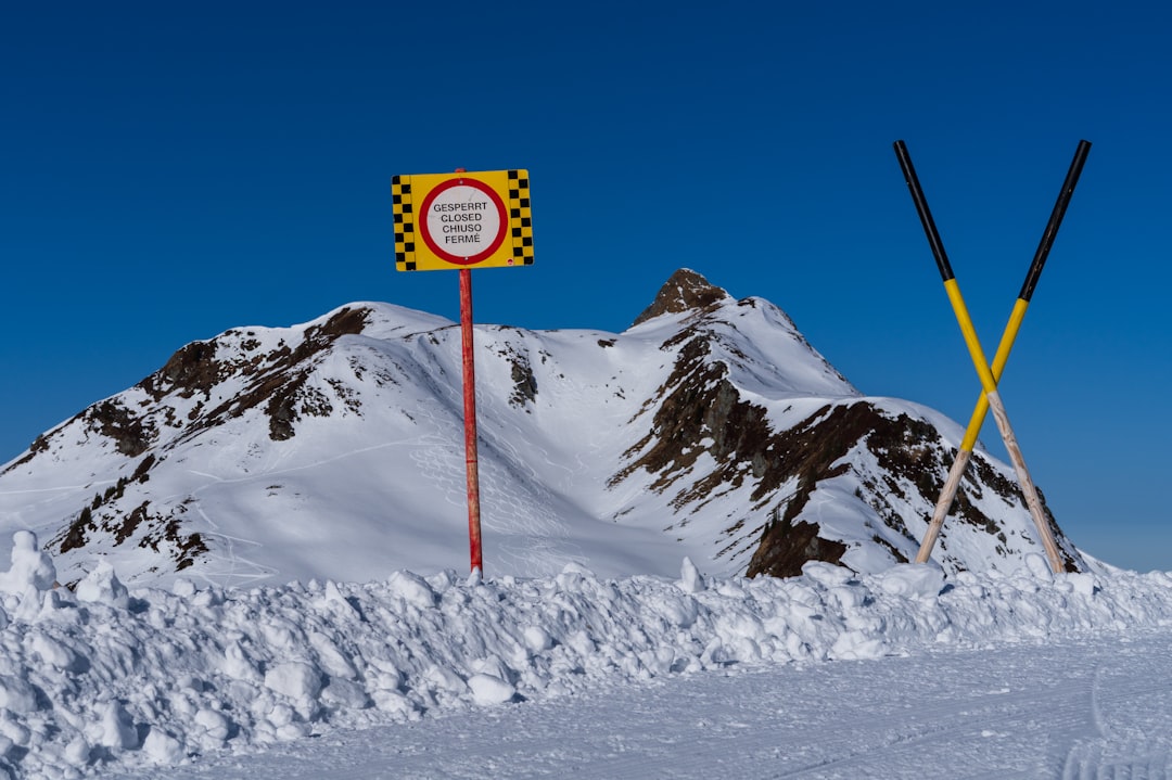 A snow covered mountain with a sign in the foreground, Road to nowhere