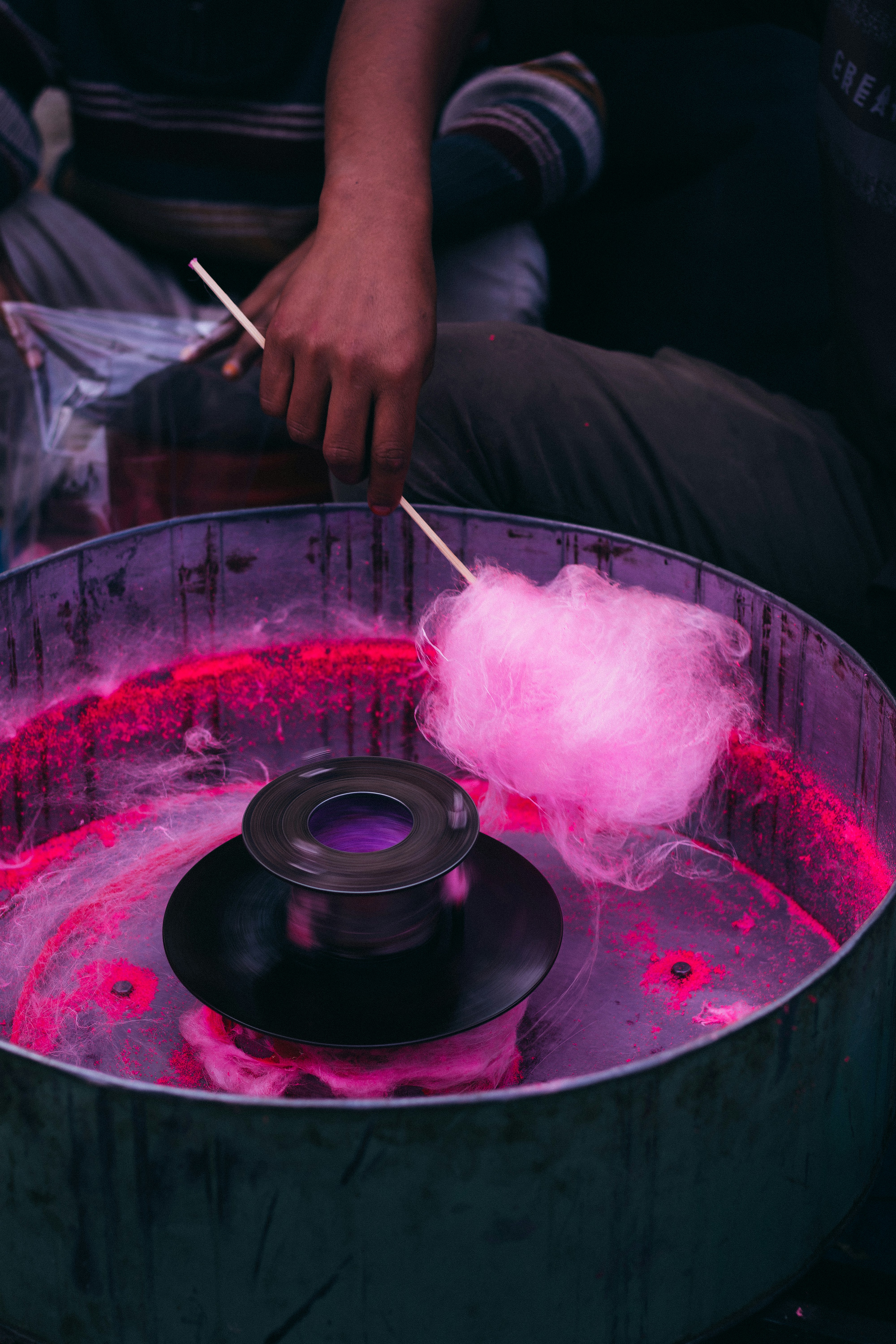 A person sitting in front of a metal bucket with a pink substance inside of it