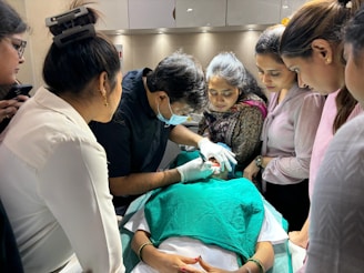 A group of people standing around a woman in a hospital bed