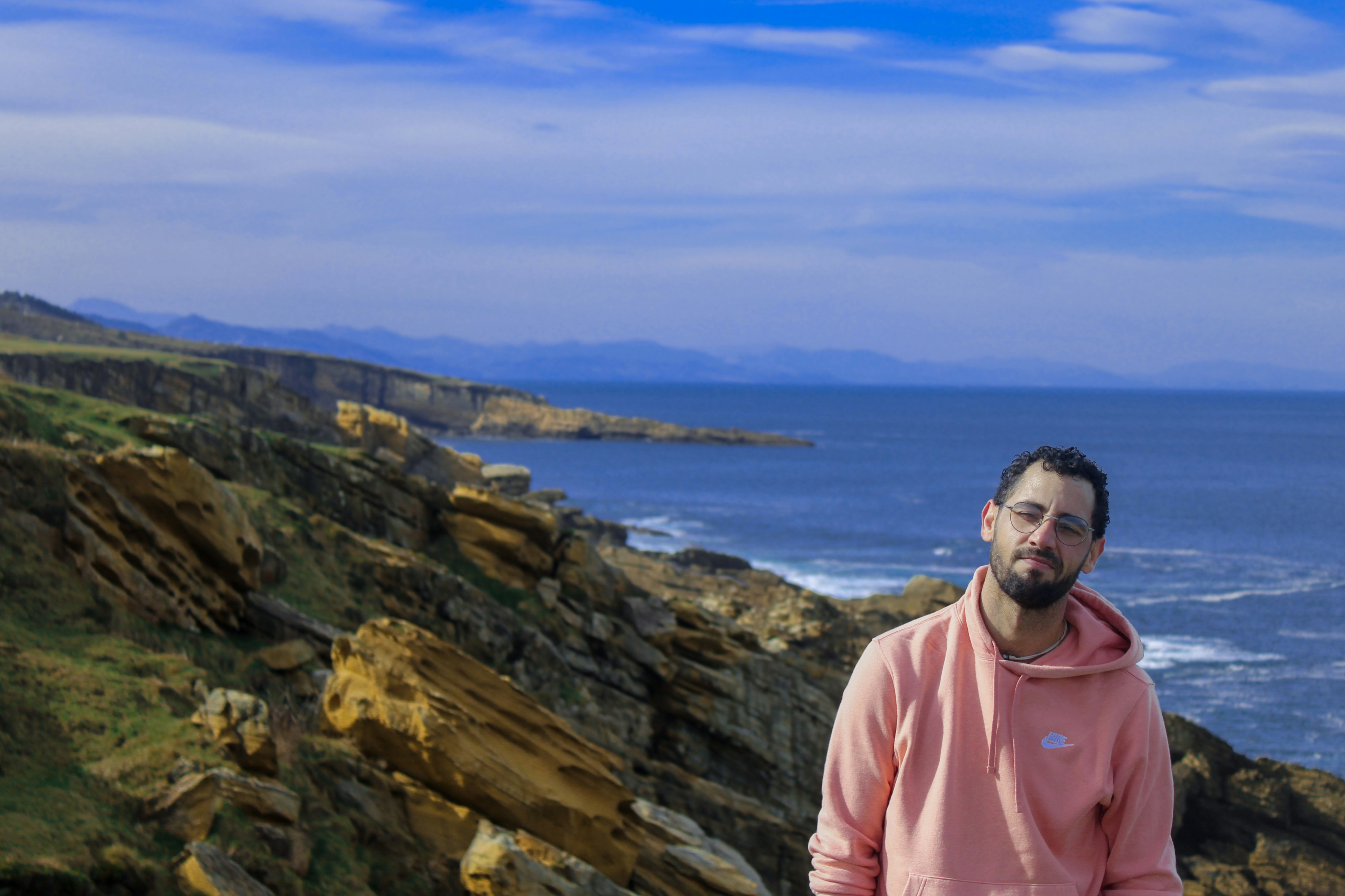 A man standing on a rocky cliff next to the ocean