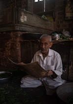 A man sitting on the ground reading a newspaper