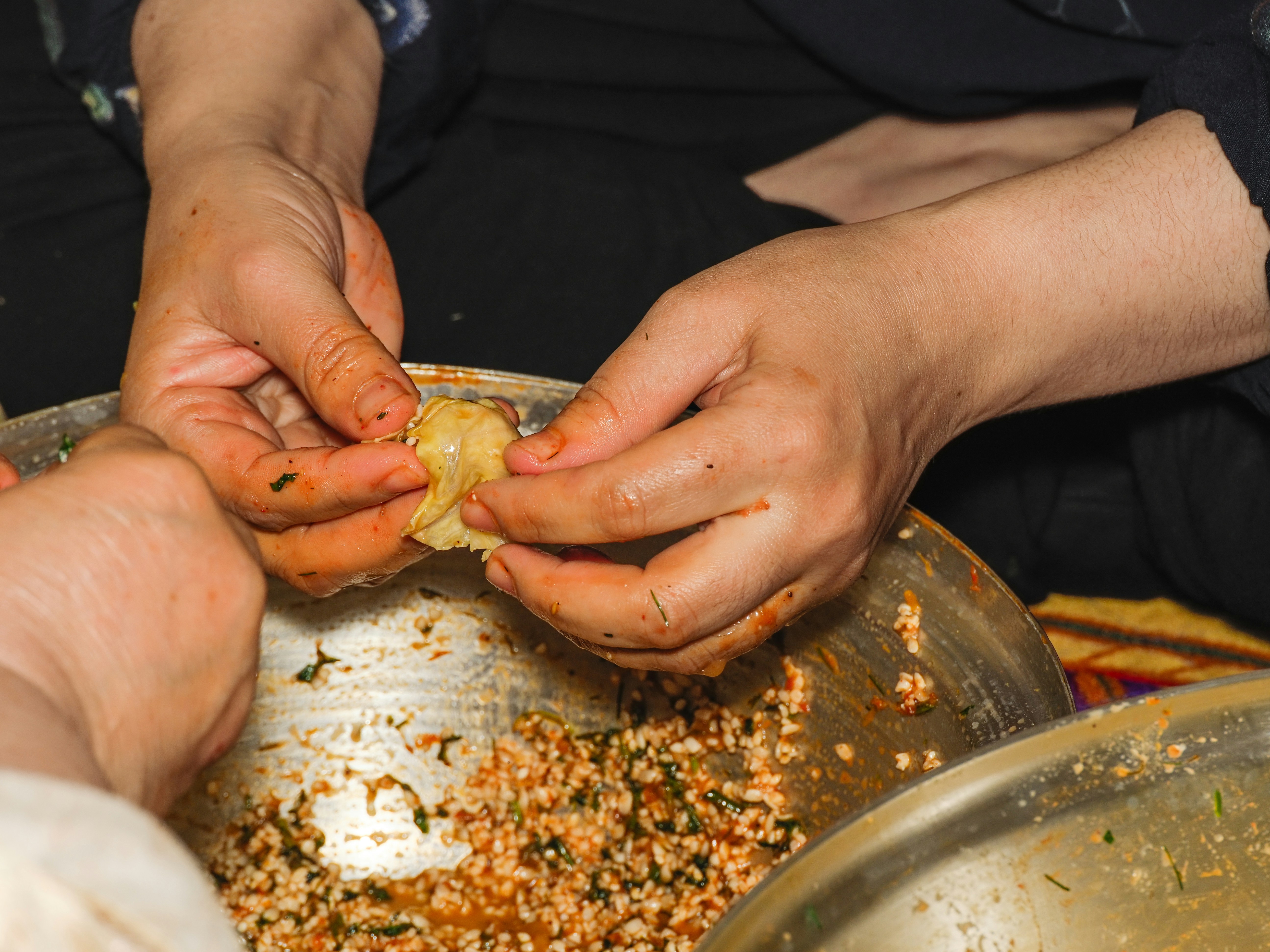 A couple of people that are putting food in a bowl