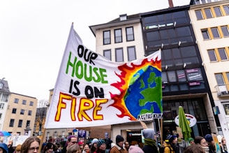 A group of people holding a sign that says one house is on fire