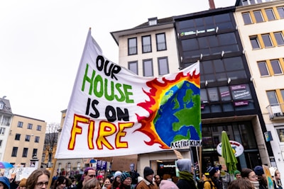 A group of people holding a sign that says one house is on fire