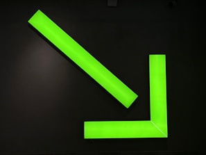 A neon green l sign on a black wall