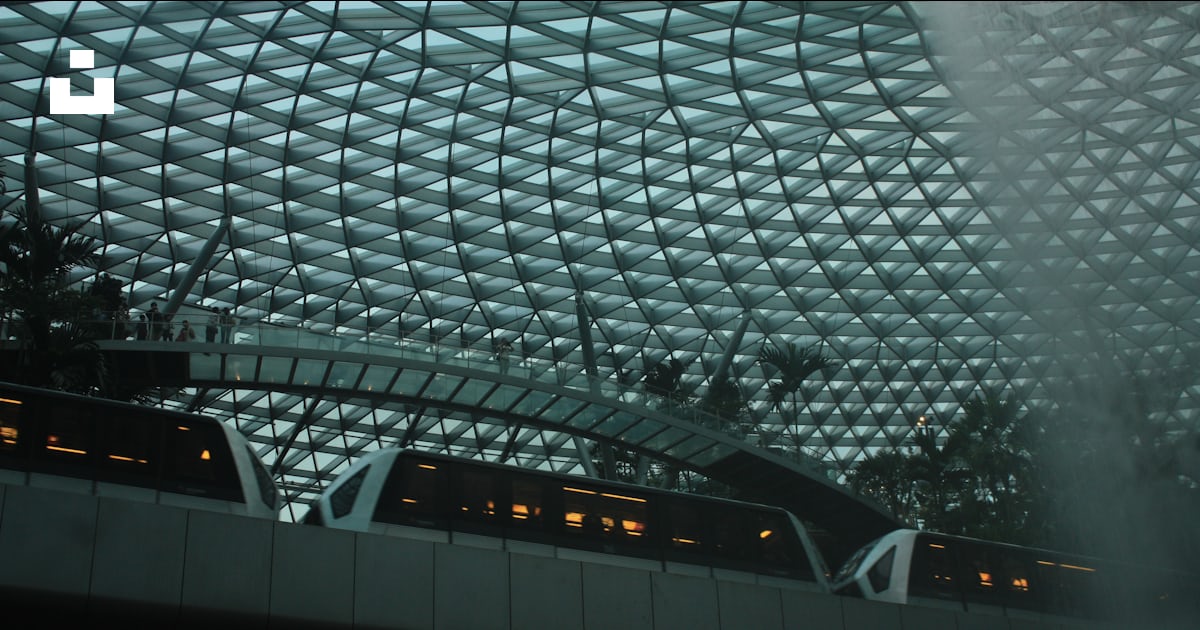 A train traveling through a train station next to a tall building photo ...