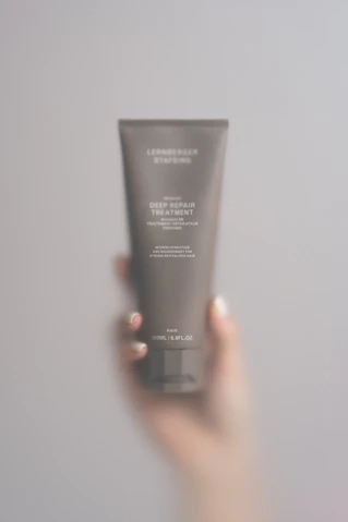 A person holding a tube of cream in their hand