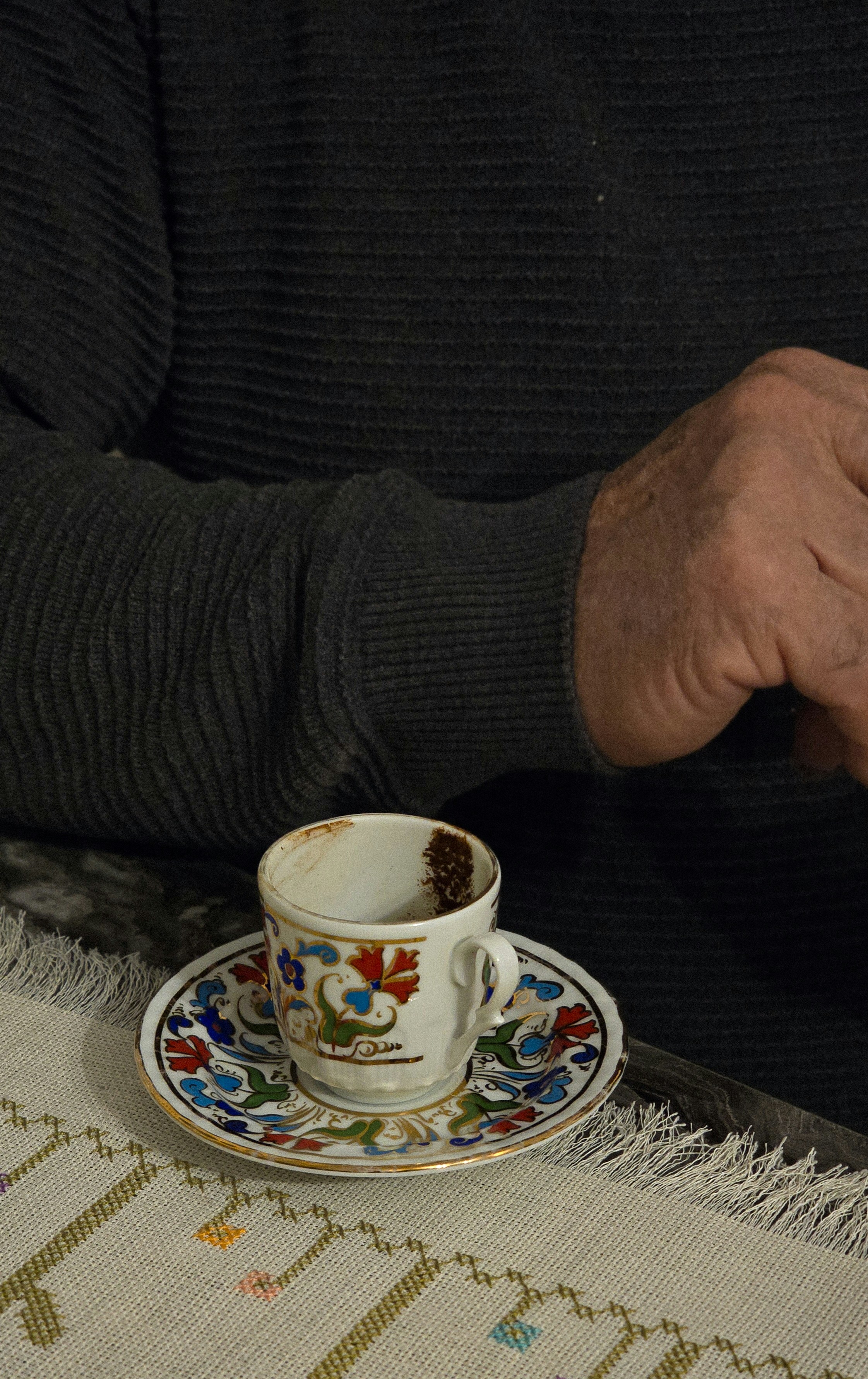 A man sitting at a table with a cup of coffee