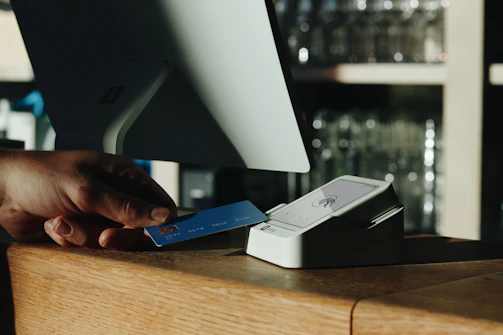 A person holding a credit card in front of a computer