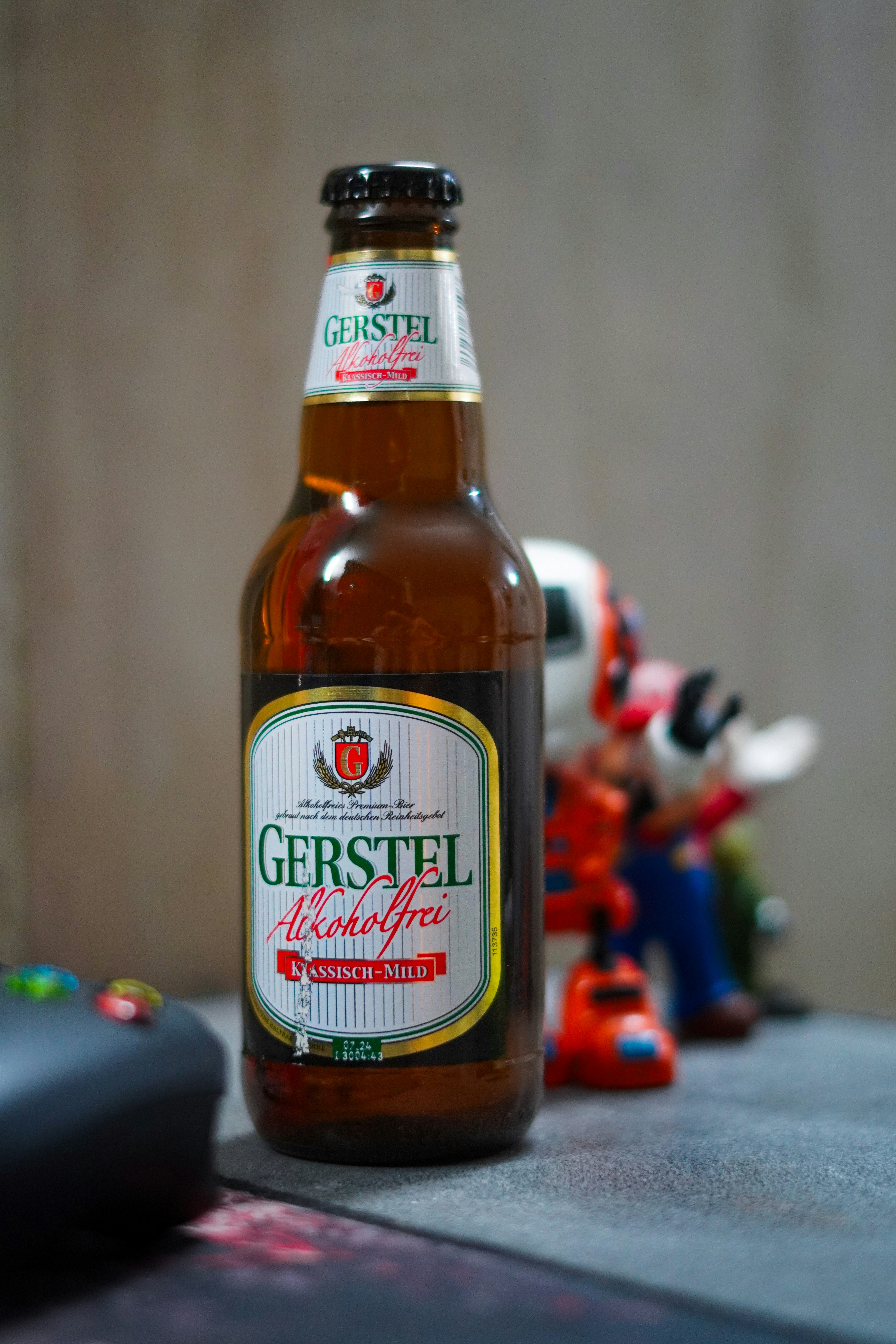 A bottle of beer sitting next to a remote control