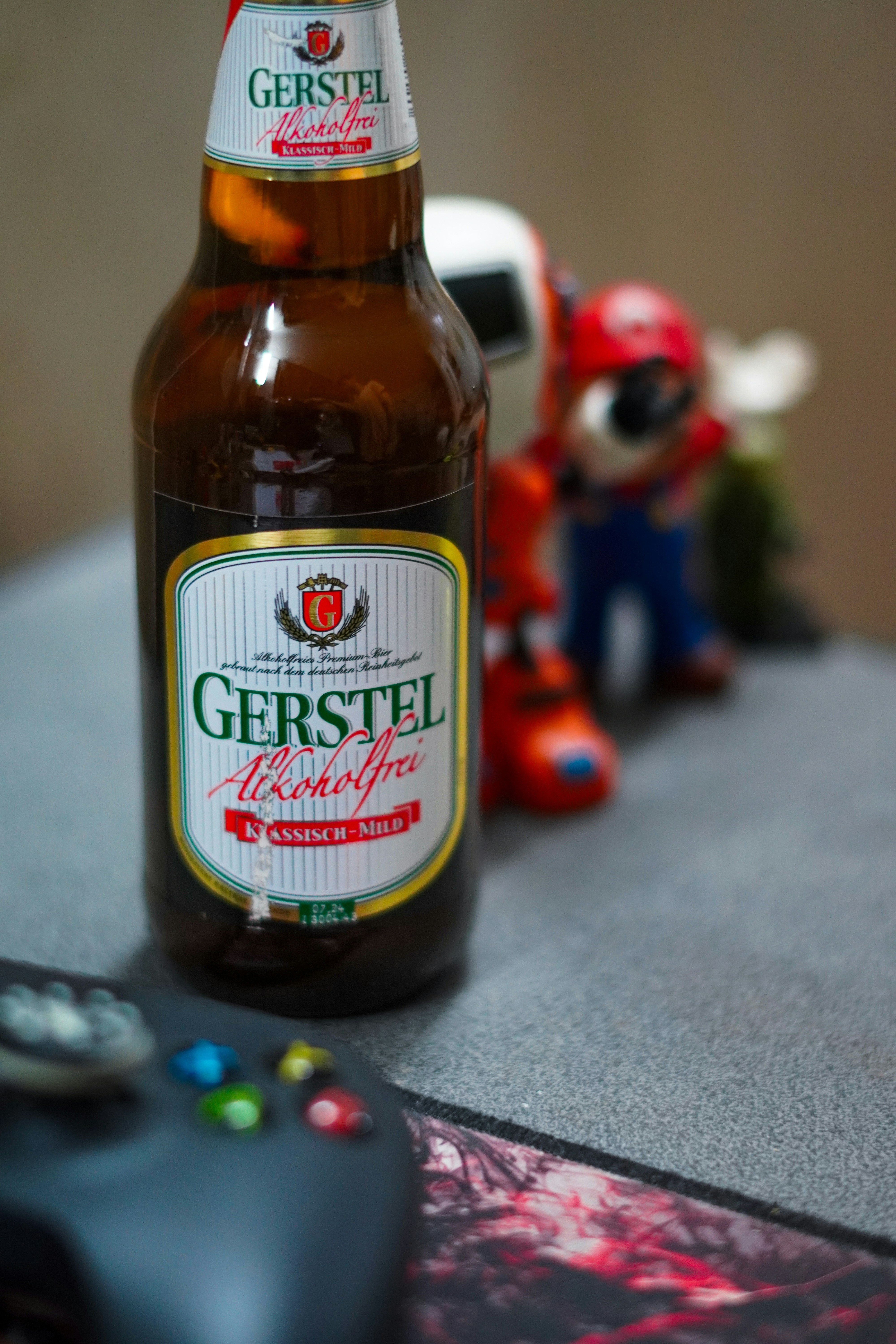 A bottle of beer sitting next to a game controller
