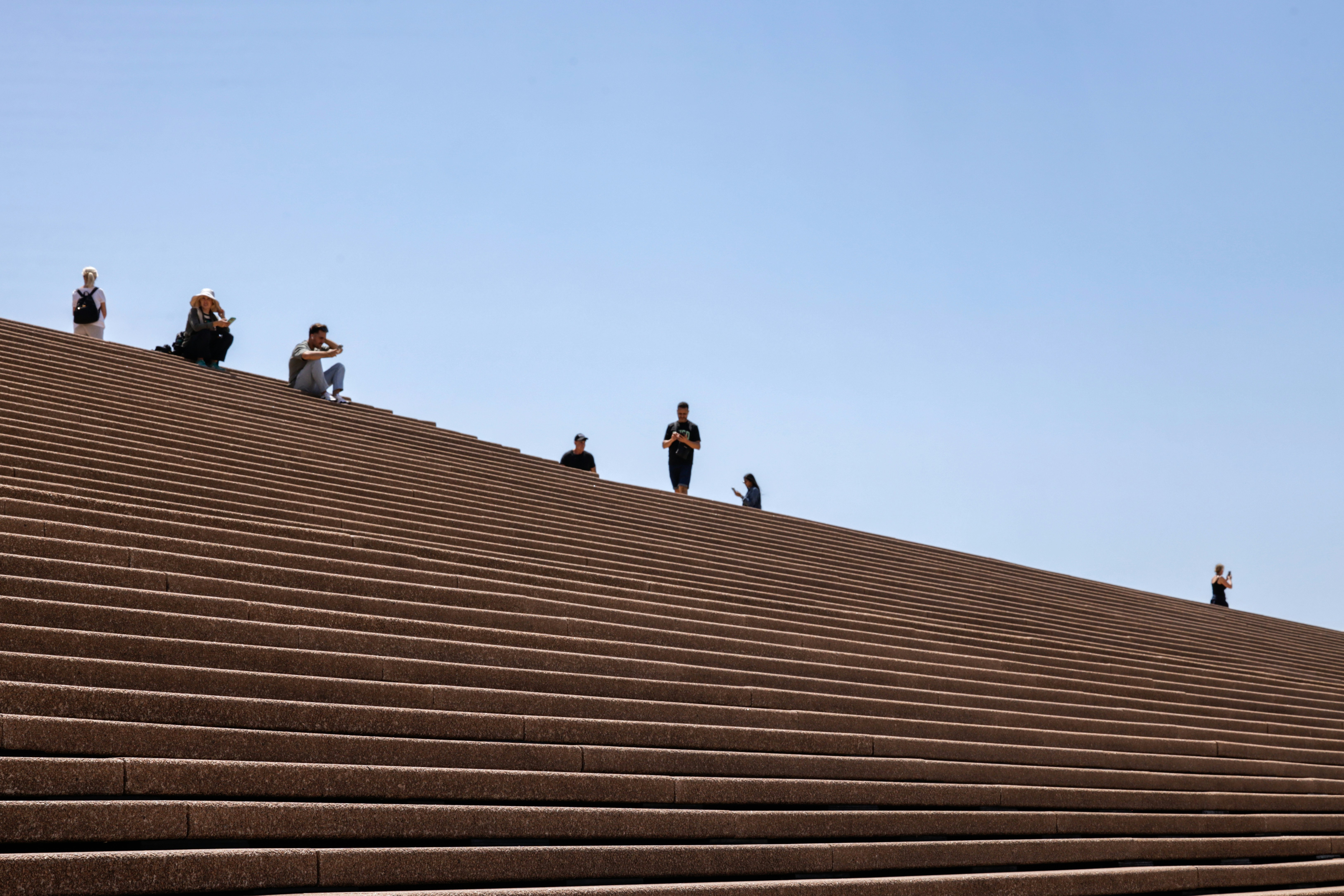 Um grupo de pessoas em pé em cima de uma arquibancada marrom do estádio