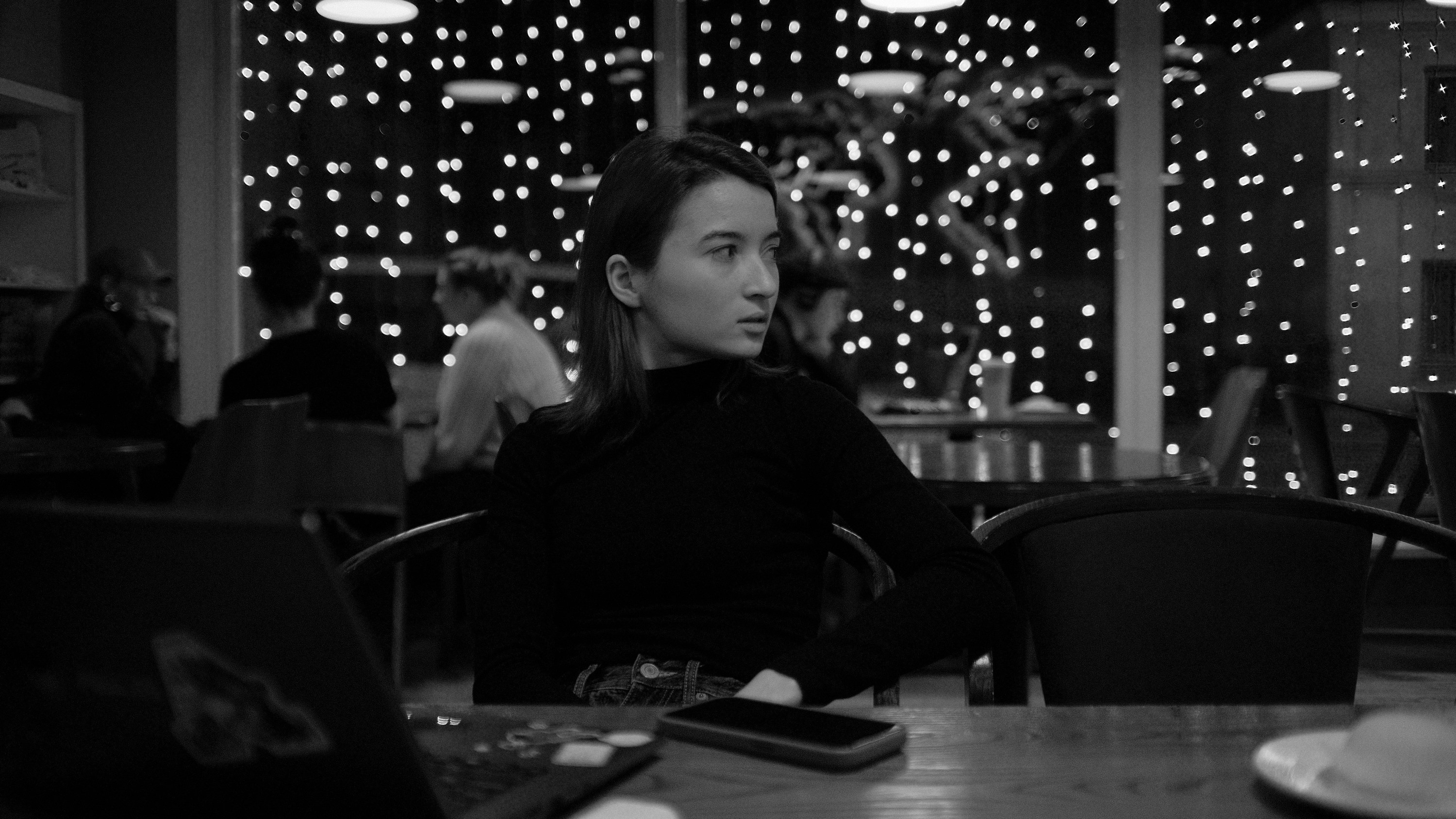 A woman sitting at a table in front of a laptop computer