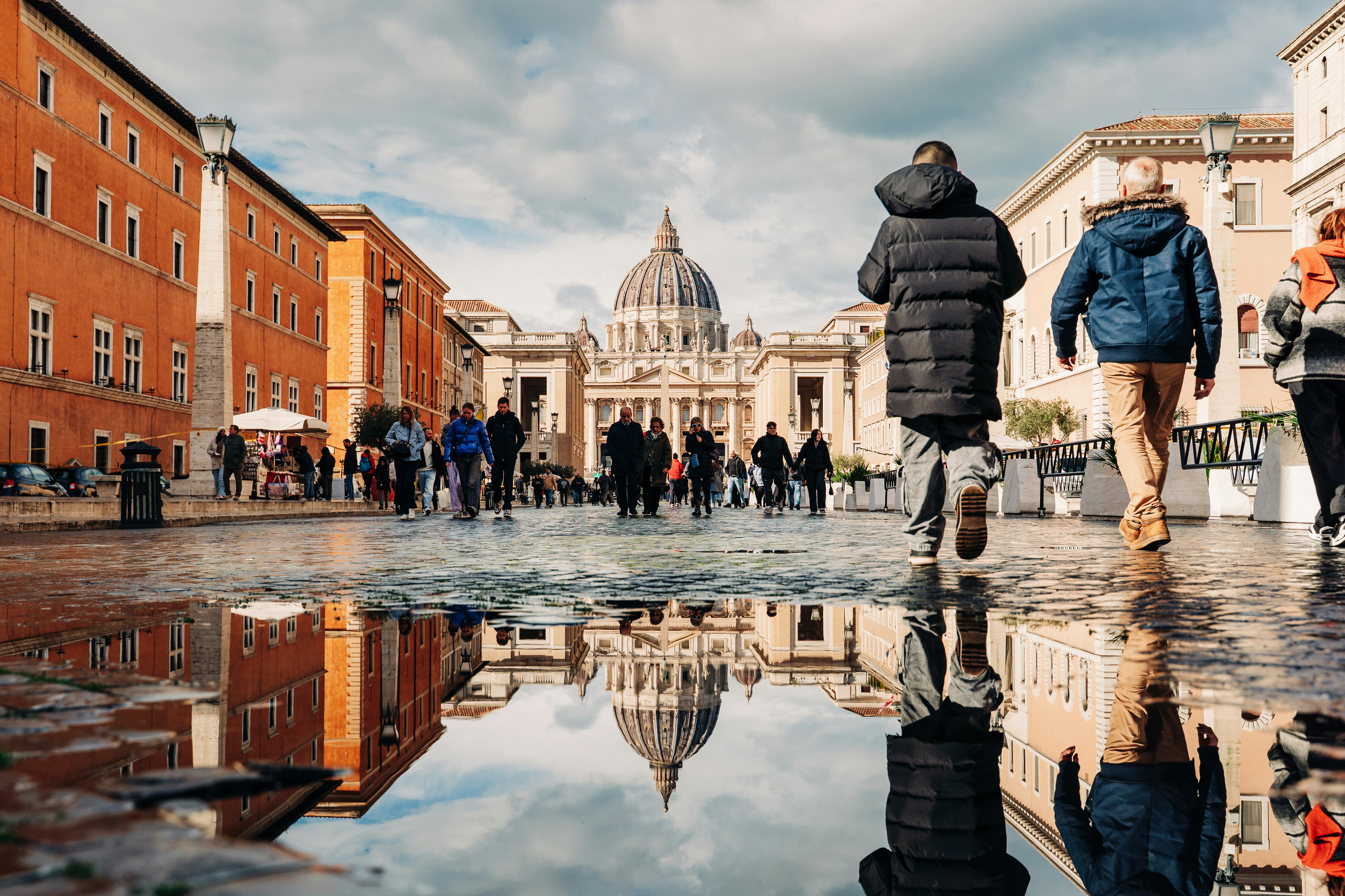 A group of people walking down a street next to tall buildings