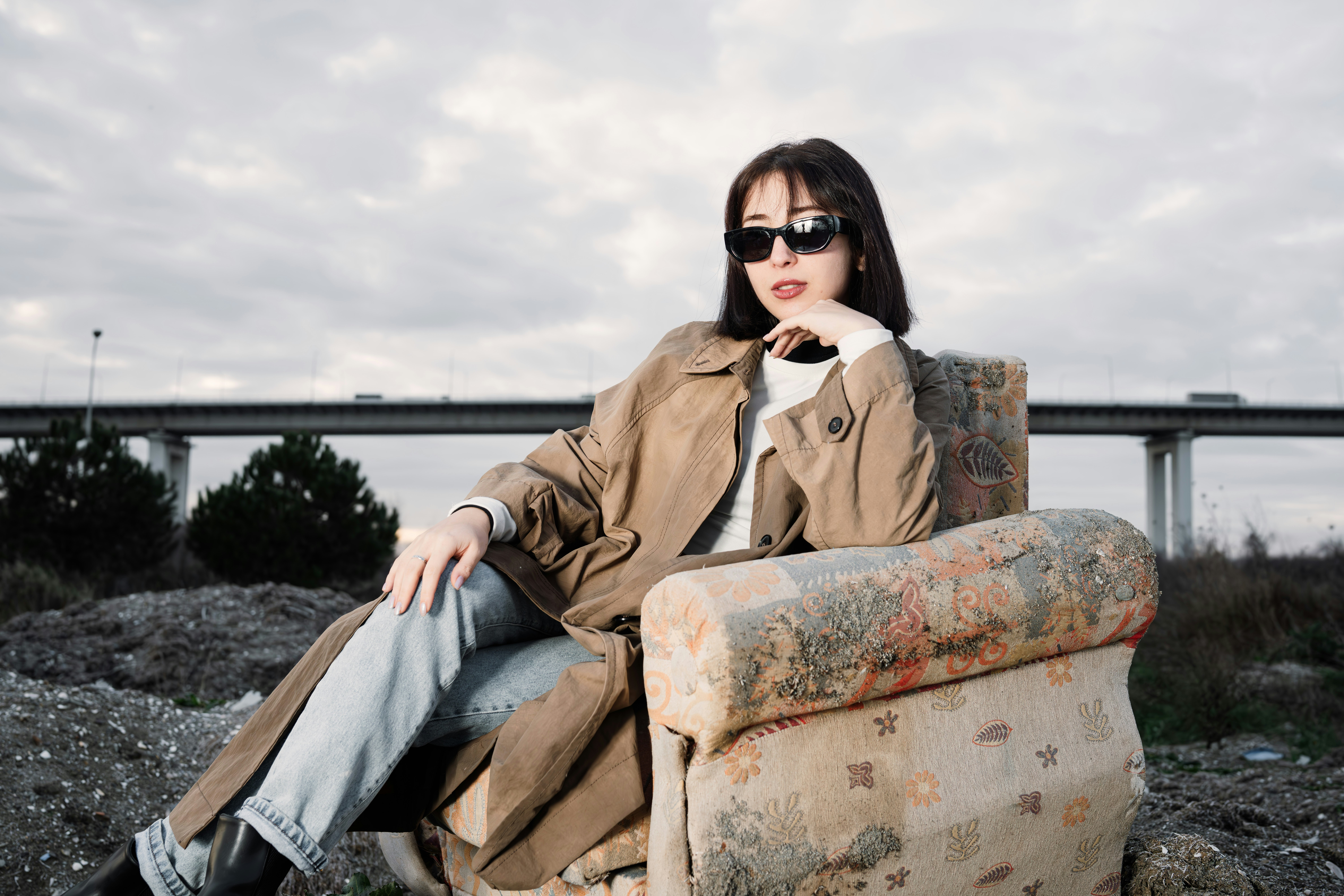 A woman sitting in a chair with a bridge in the background