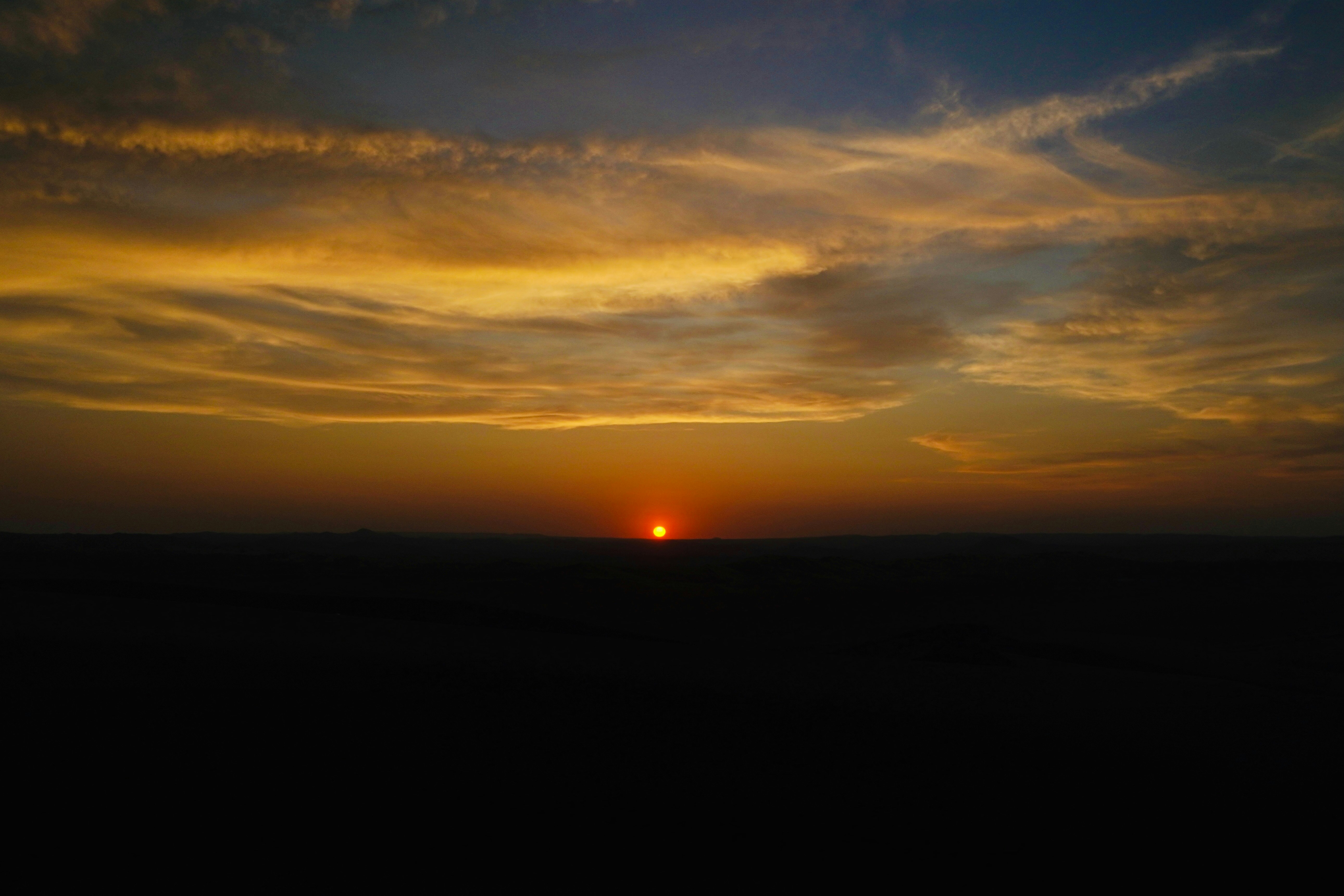 The sun is setting over the horizon of a field