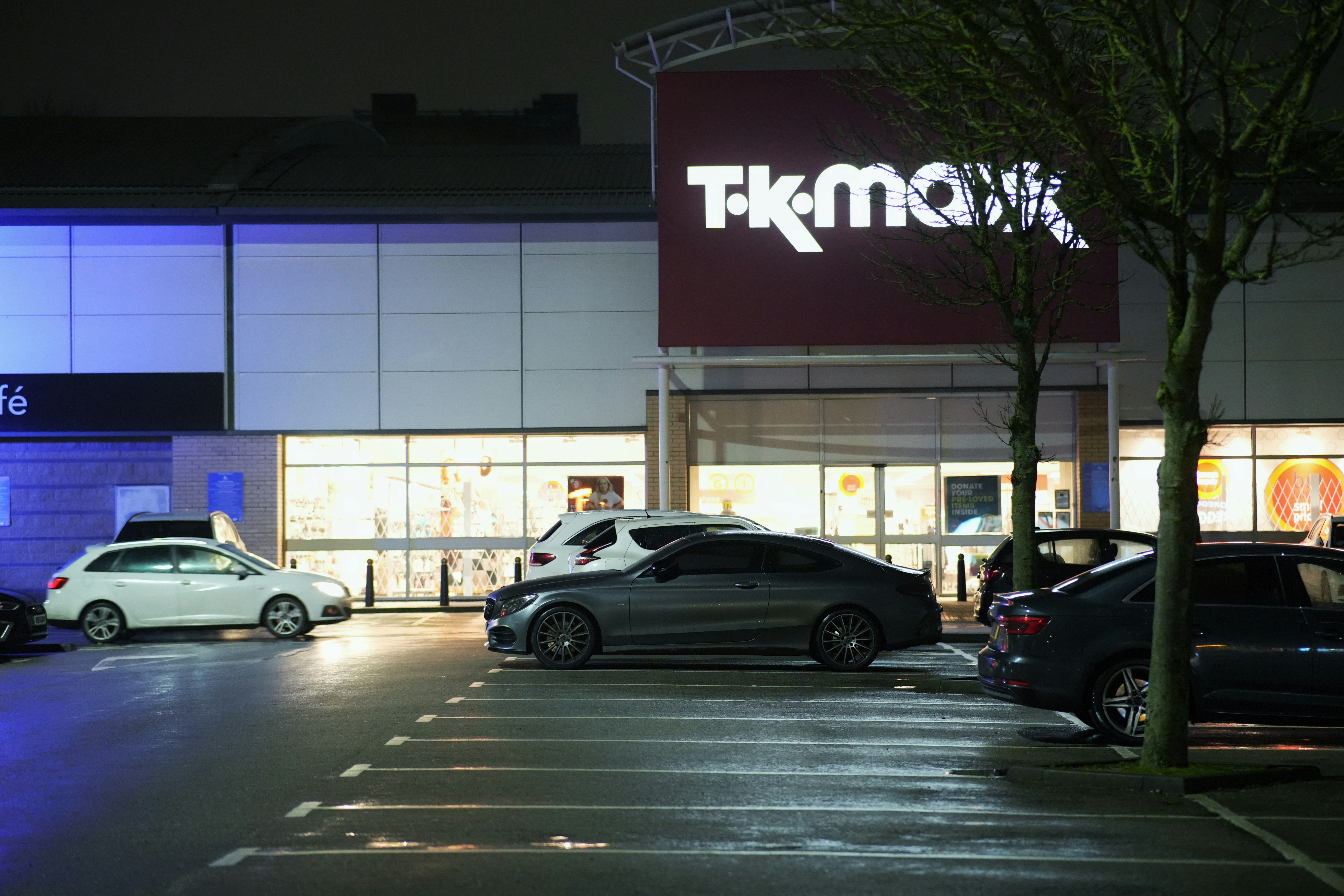 A store with cars parked in front of it at night