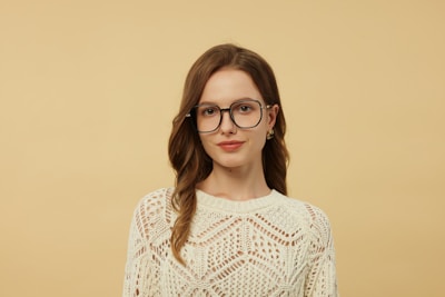 A woman wearing glasses standing in front of a wall