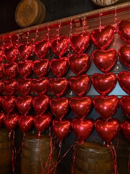A bunch of red heart shaped balloons hanging on a wall
