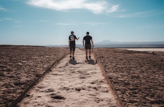 A couple of men walking down a dirt road