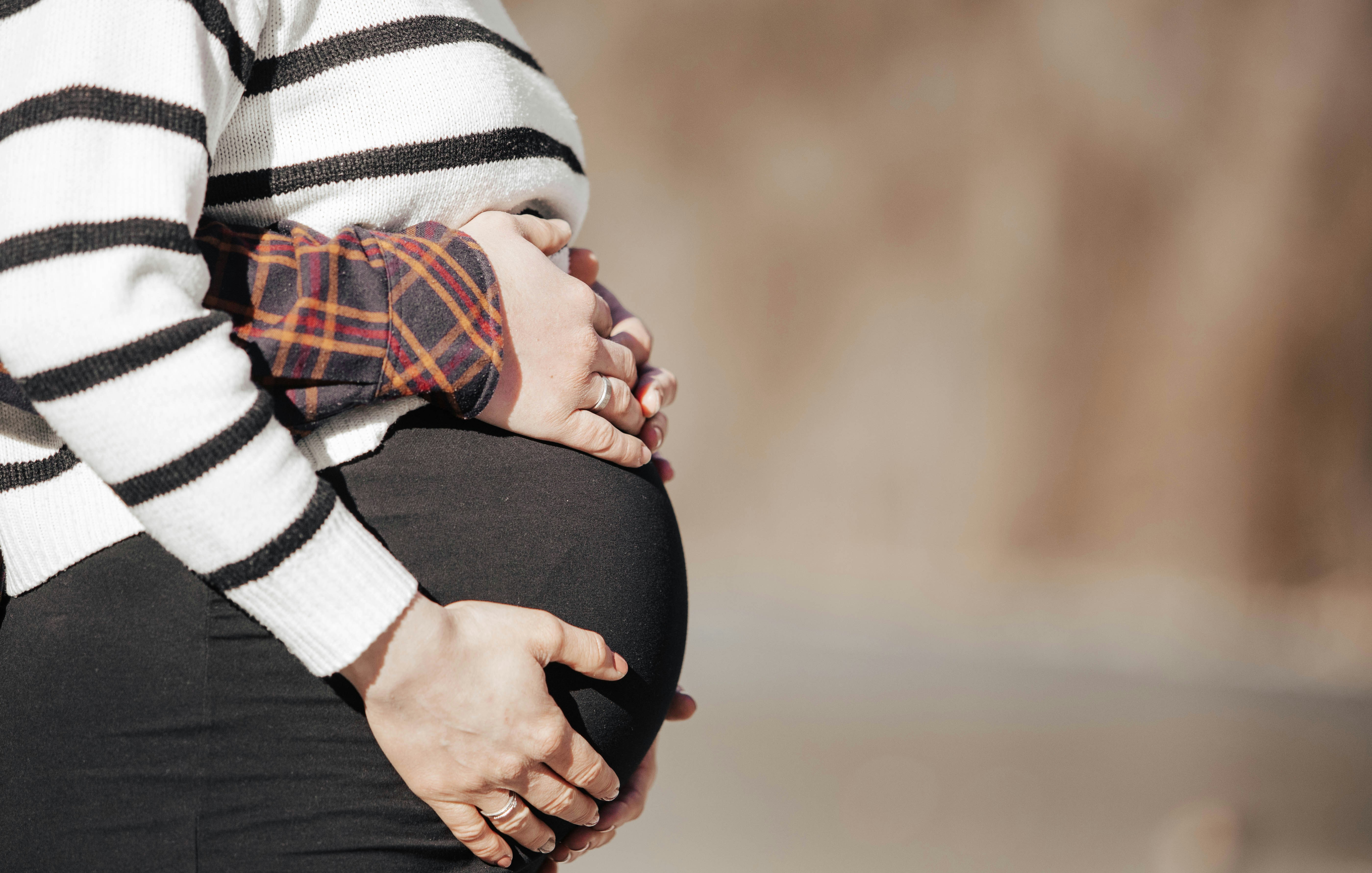 Une femme enceinte en chemise rayée et pantalon noir