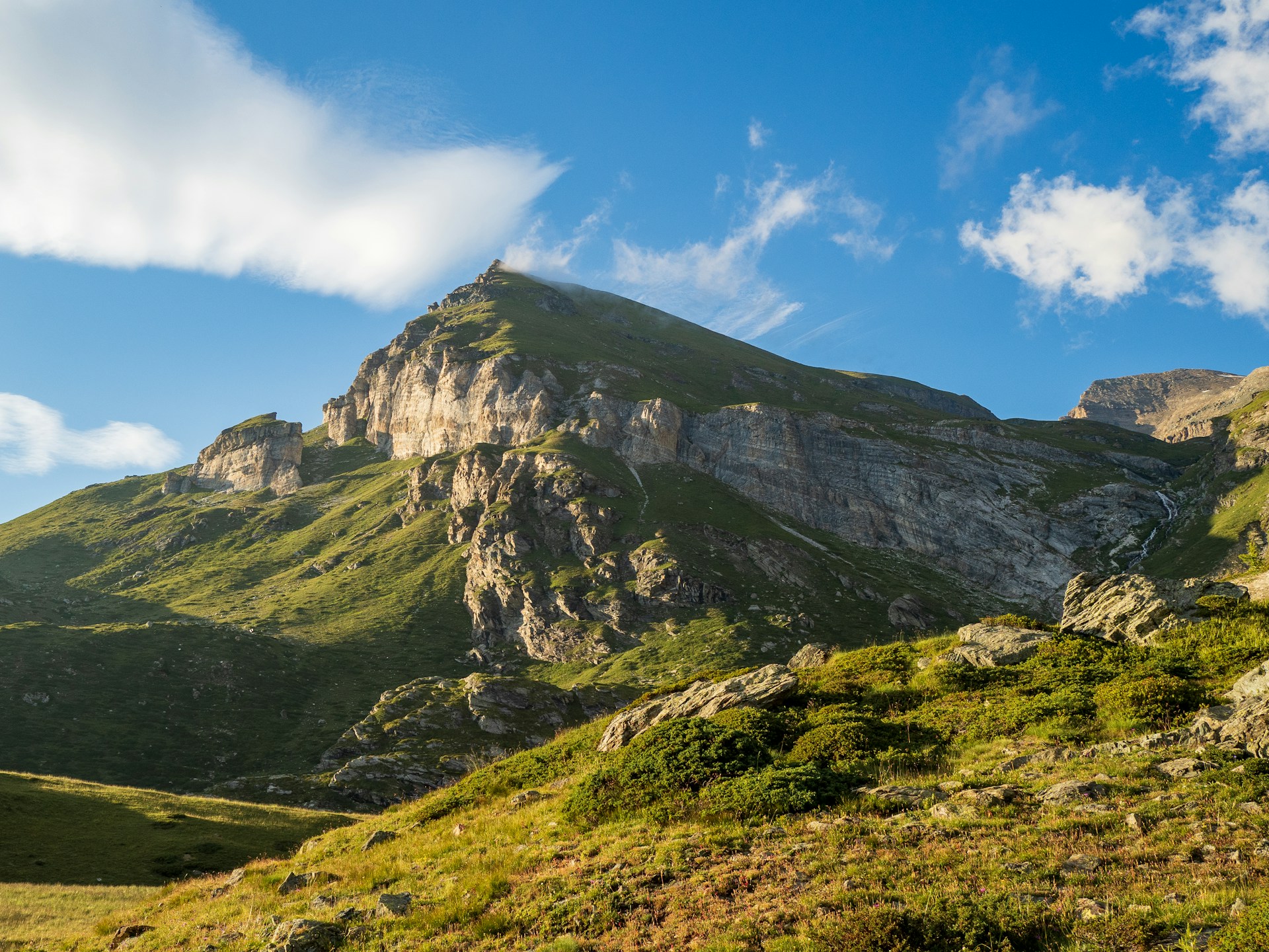 A mountain with a grassy field below it