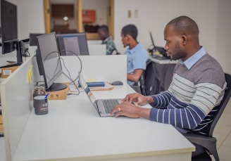 A man sitting at a desk using a laptop computer