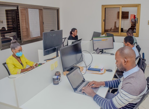 A group of people sitting around a table with laptops