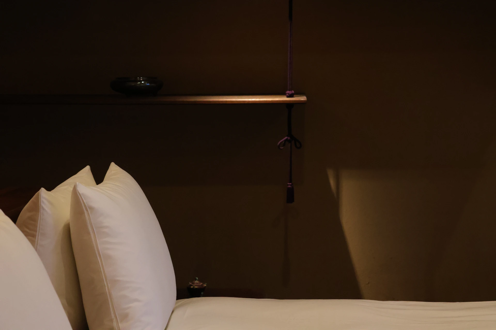 A bed with white sheets and pillows in a room