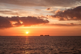 A sunset over the ocean with a boat in the distance