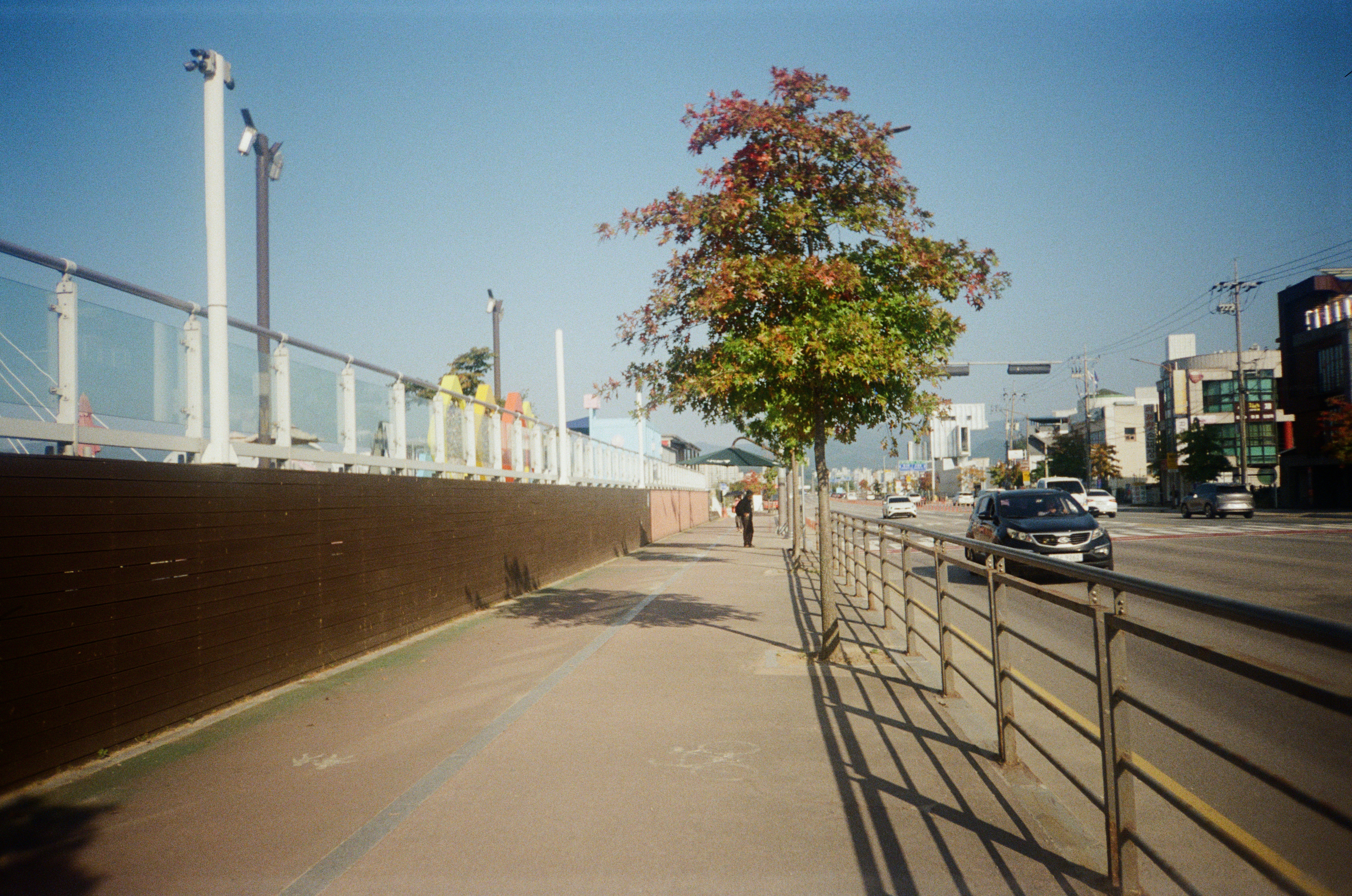 Eine Person, die neben einem Zaun einen Bürgersteig entlanggeht