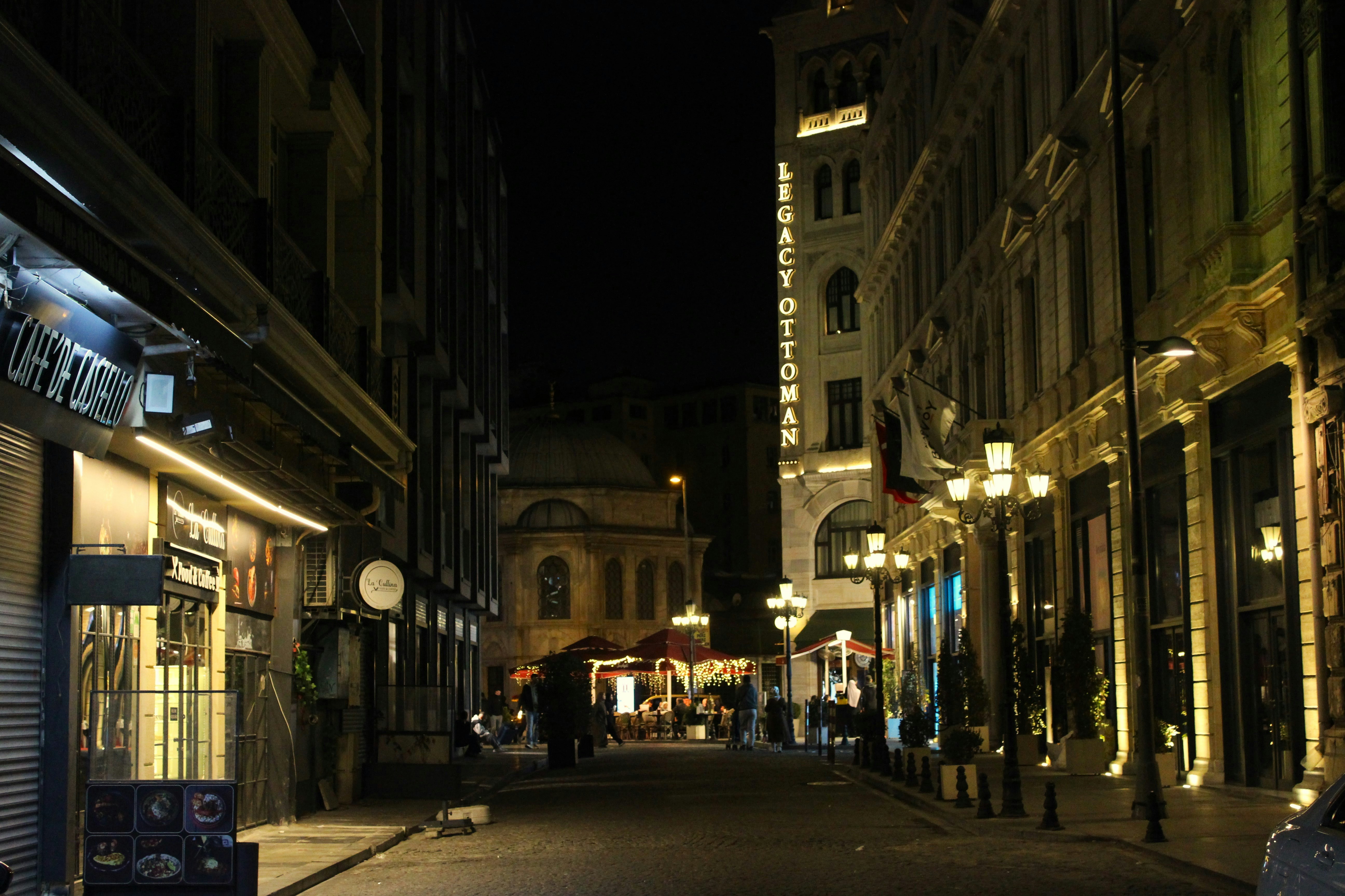 A city street at night with people walking on the sidewalk