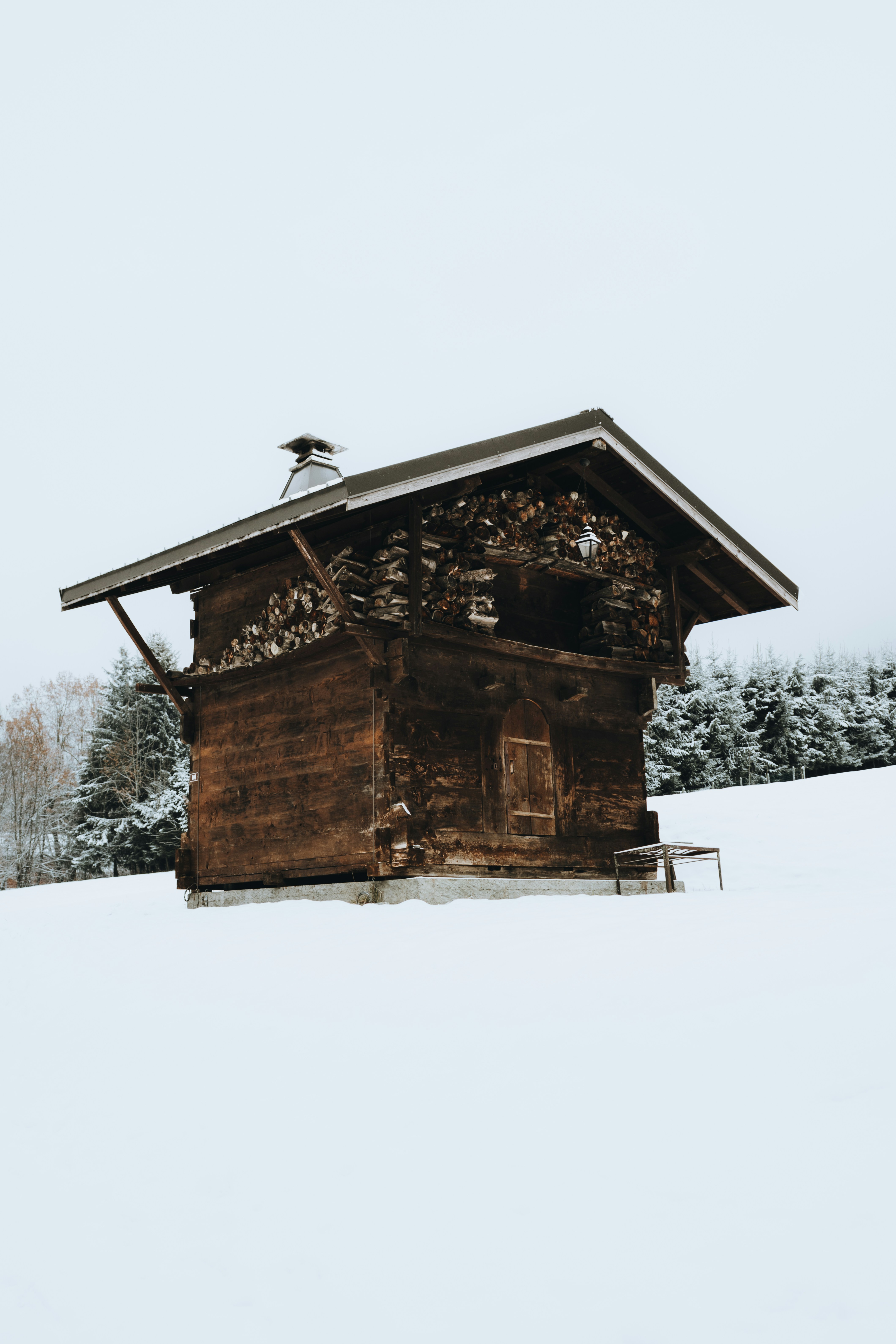 A small wooden building sitting in the middle of a snow covered field