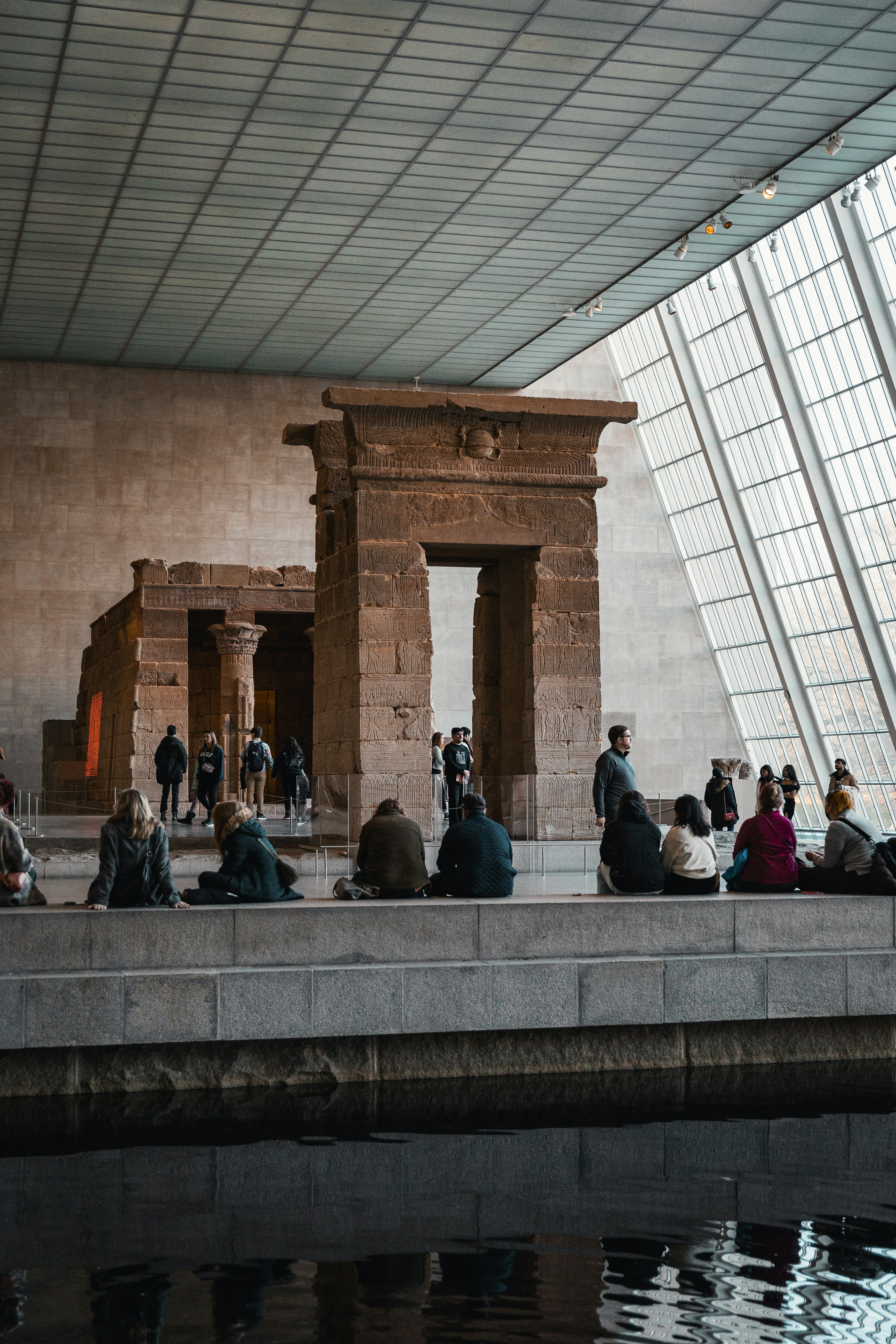 A group of people sitting on a bench next to a body of water