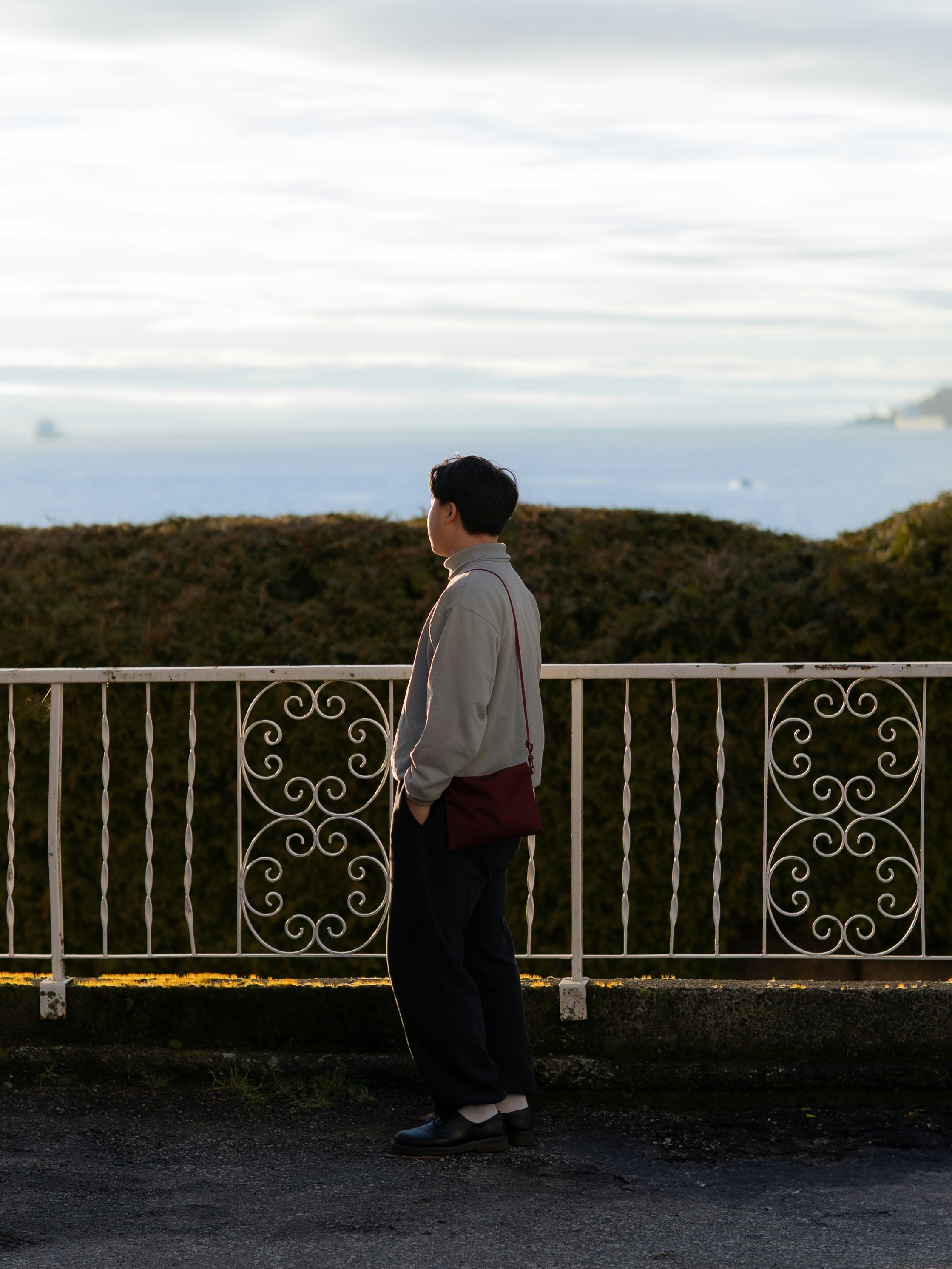 Um homem parado na beira de uma estrada ao lado de uma cerca