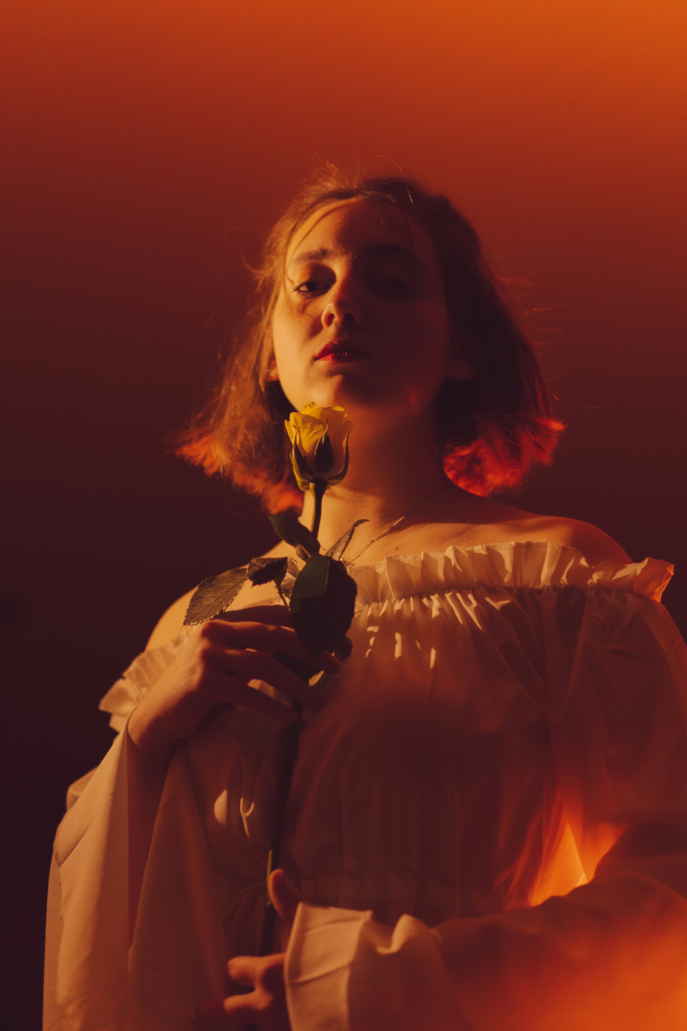 Uma mulher em um vestido branco segurando uma rosa