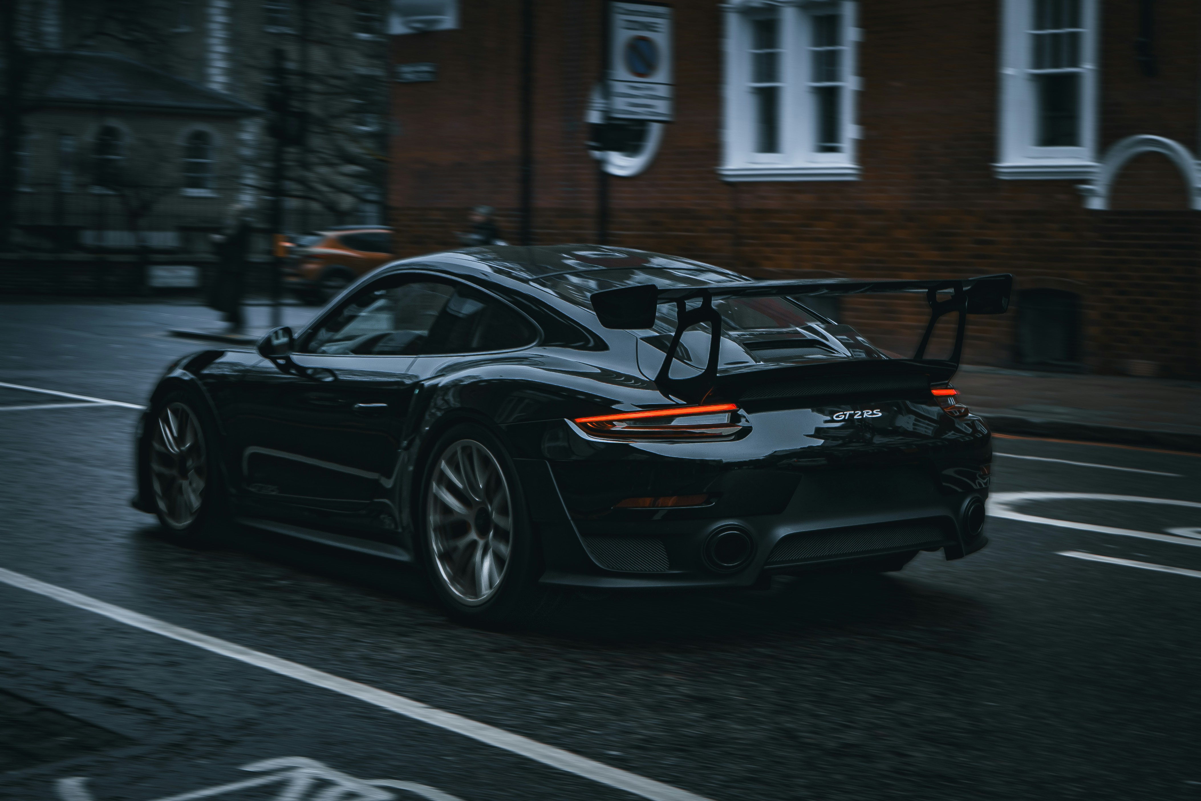 A black sports car driving down a city street photo – Free Car Image on ...