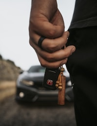 A person holding a car key with a car in the background