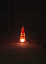 A traffic cone sitting on the ground at night