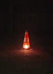 A traffic cone sitting on the ground at night