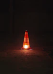 A traffic cone sitting on the ground at night